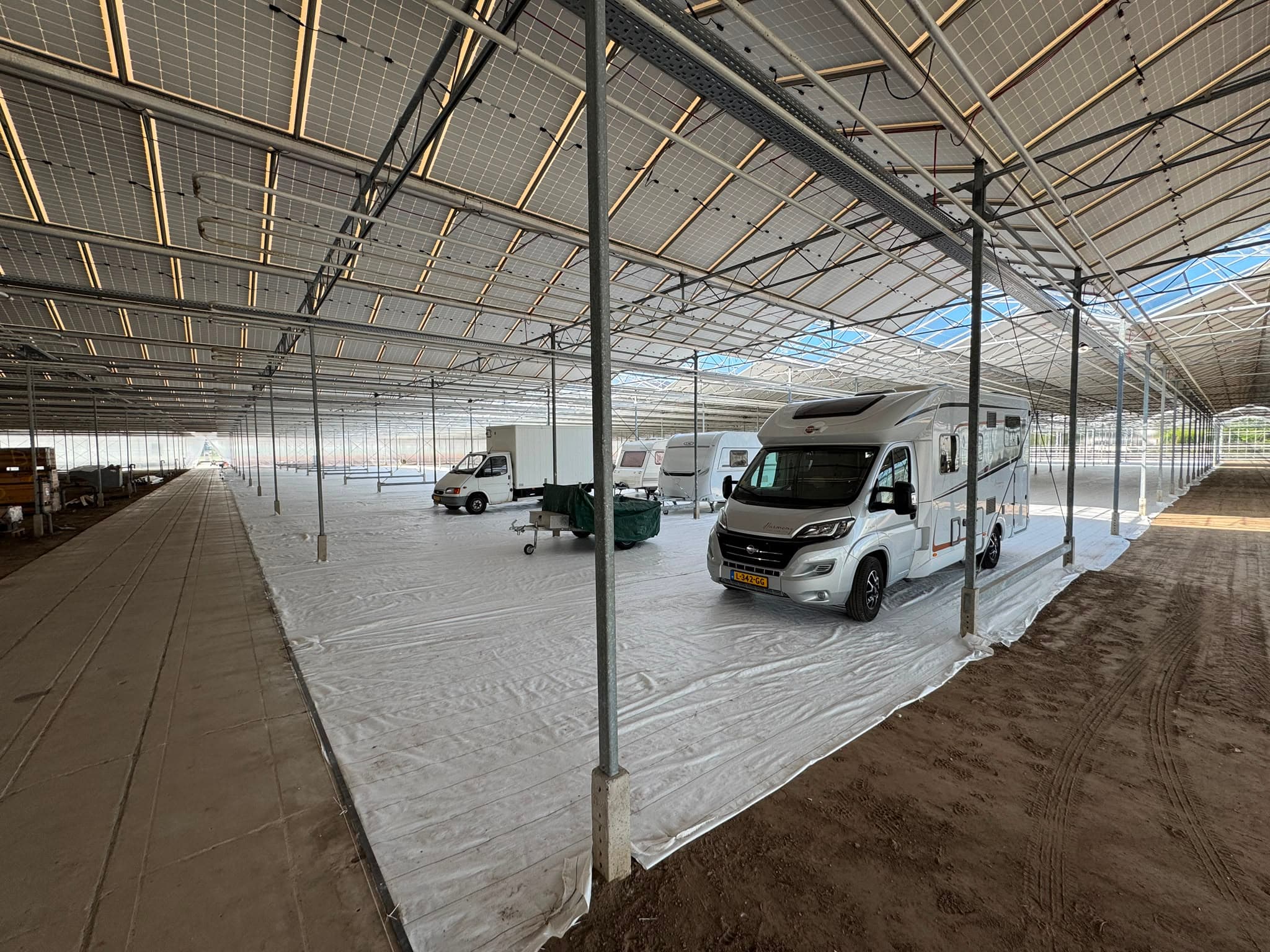 Camper gestald tussen andere voertuigen in de glazen kas